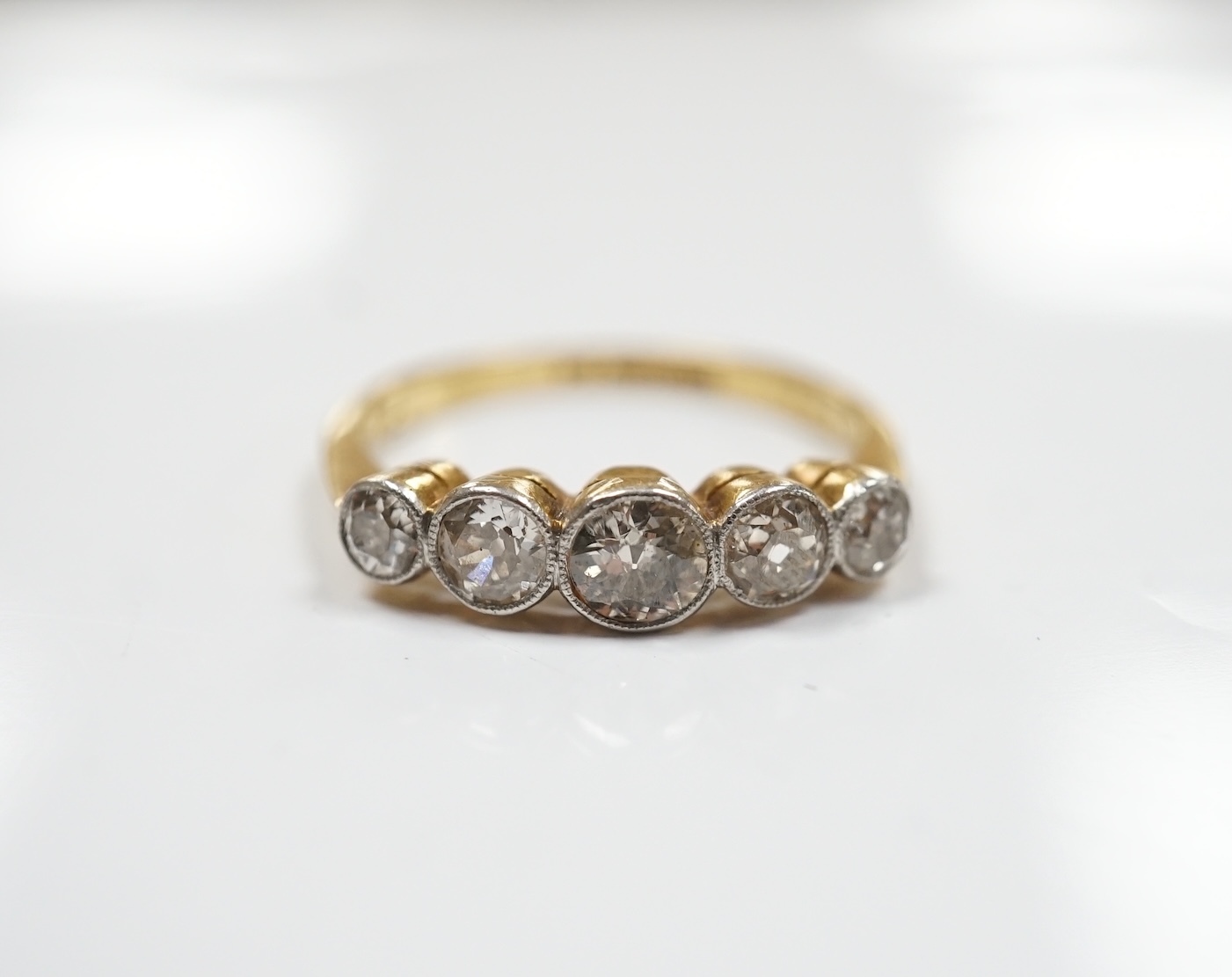 An 18ct, plat and graduated five stone collet set diamond half hoop ring, size M, gross weight 2.7 grams. Condition - poor to fair